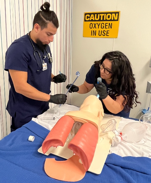 Student Giovanna Sosa (right) and fellow second-year student Oscar Quiroz work with a simulated patient in a respiratory therapy lab instructional session.